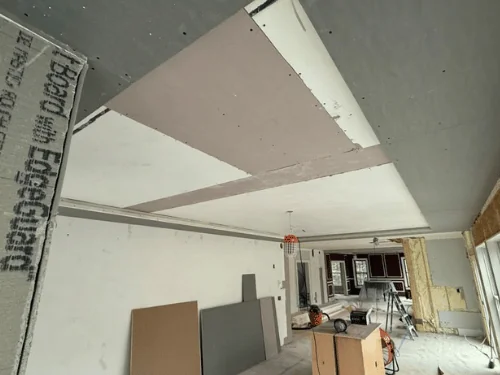 New drywall ceiling panels meeting a soffit, board edges still bare before taping