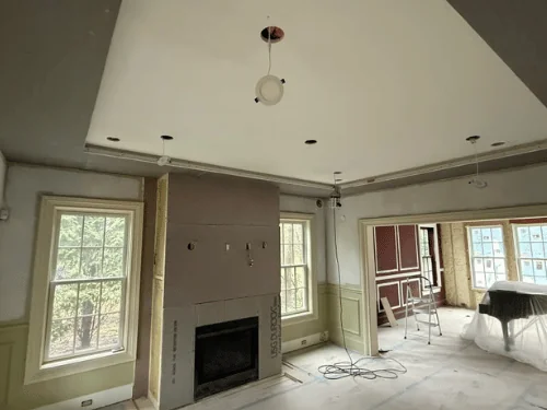 Room with a finished ceiling and a fireplace wall sheathed in board, green wainscot on the sides