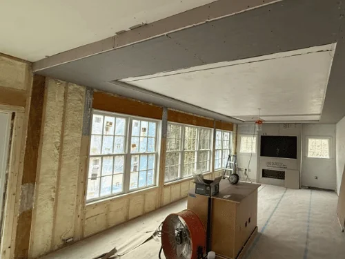 Large room with a new drywall ceiling and soffit, walls still open to spray foam insulation