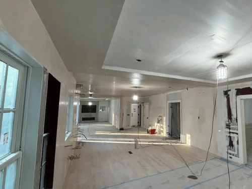 Long living room after drywall, ceiling soffit and walls finished smooth, TV wall at the far end
