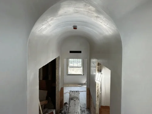 Pointed vaulted ceiling finished in plaster over a hallway with doors on both sides