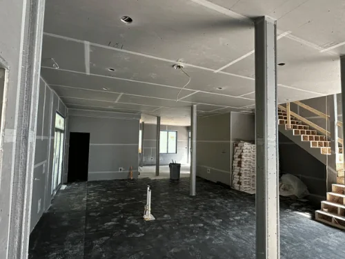 Basement in blueboard with taped joints, boxed columns and bags of plaster staged by the stairs