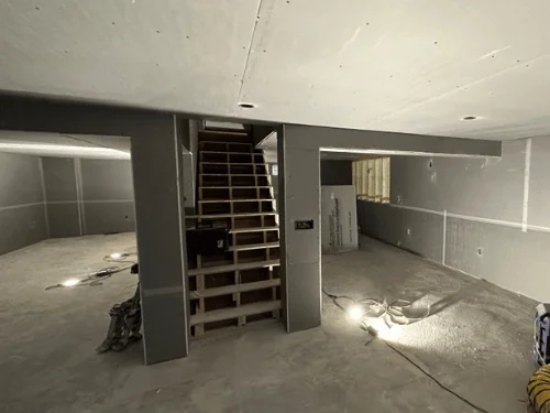 Basement in blueboard with taped joints, the stair wall wrapped in board