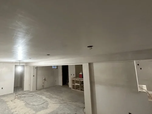 Finished basement with smooth plaster walls and ceiling and a boxed column