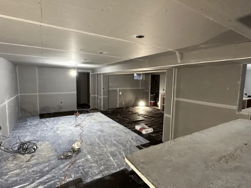 Basement with a long soffit and walls in blueboard, joints taped and the floor covered