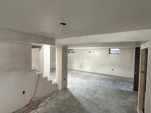Basement with a plastered beam soffit, a stepped stair wall and doorways to the next rooms