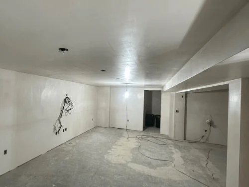 Plastered basement room with a beam soffit and wiring left out for fixtures