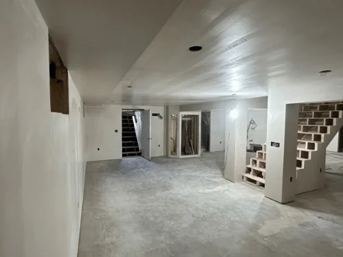 Basement stair and bulkhead entry seen past a smooth plaster wall