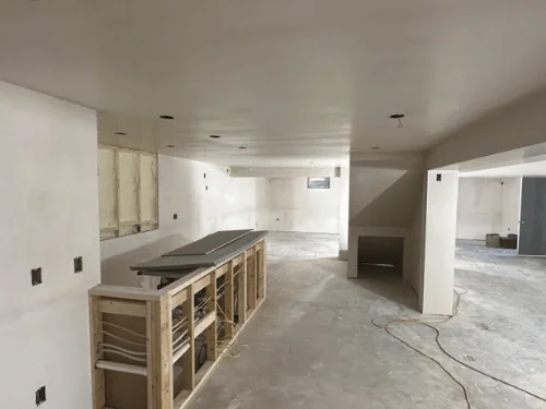 Basement bar framed in front of plastered walls and a beam soffit