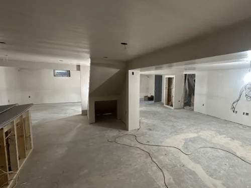 Basement with a stepped beam soffit and smooth plaster walls around the bar area