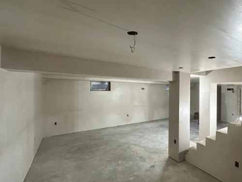 Basement with a boxed column, a plastered stair wall and a small window