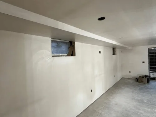 Plastered basement wall with a long beam soffit and a window return