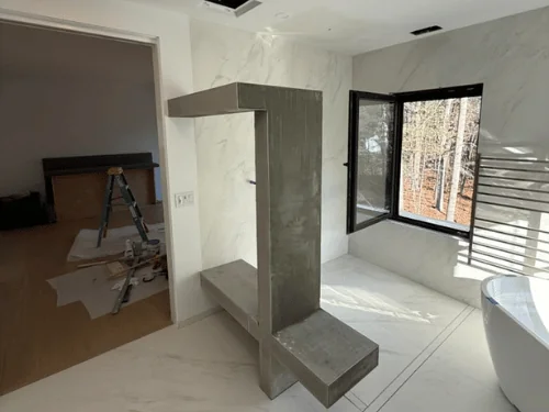 Floating bathroom bench and frame finished in gray troweled plaster, marble-look walls around it
