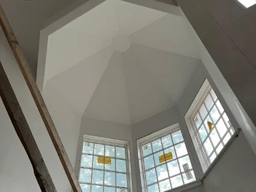 Faceted ceiling rising over a three-window bay, finished in smooth plaster
