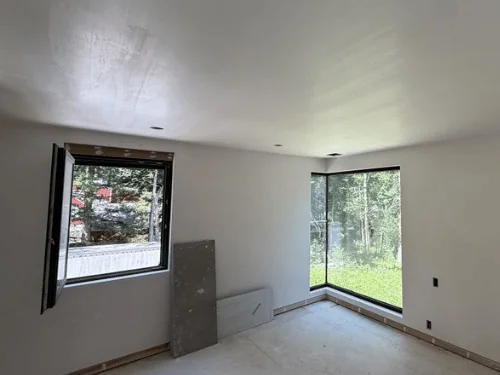 Bedroom with a glass corner window and walls and ceiling in white plaster