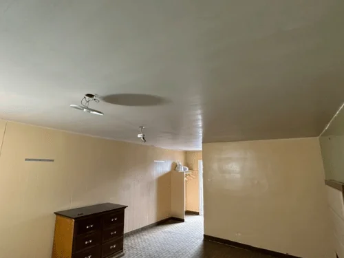 Bedroom with a newly plastered ceiling above existing painted walls and an old dresser