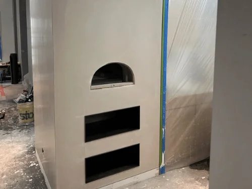 Chimney wall with an arched opening and two rectangular niches, finished in smooth plaster