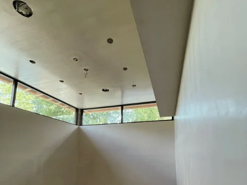 Room with a row of clerestory windows, walls and ceiling finished in smooth plaster before paint
