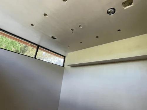 Plastered walls under clerestory windows, ceiling cut for recessed lights and a vent