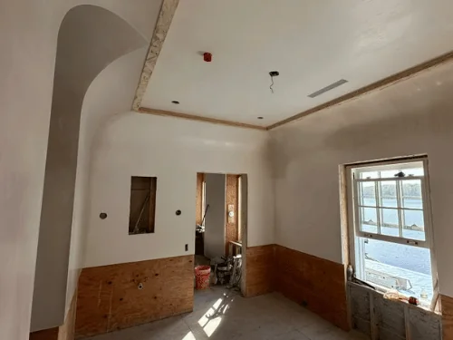 Curved plaster wall sweeping up into a coved ceiling beside a window