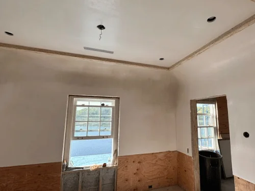 Plastered room with a coved ceiling edge and a window looking out over the water