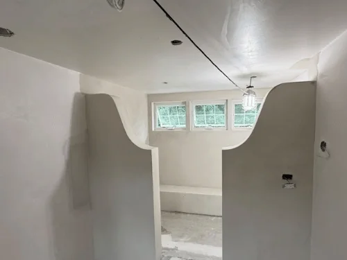 Curved plaster half-walls opening onto a bench and a row of small windows