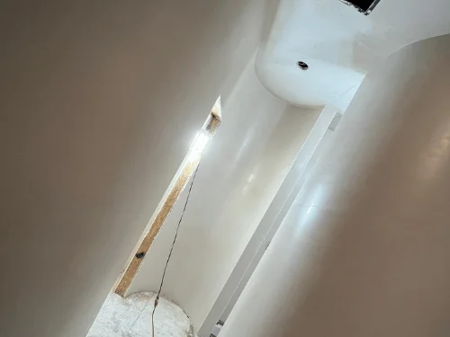 Curved plaster walls wrapping a narrow passage, the finish still showing its trowel sheen