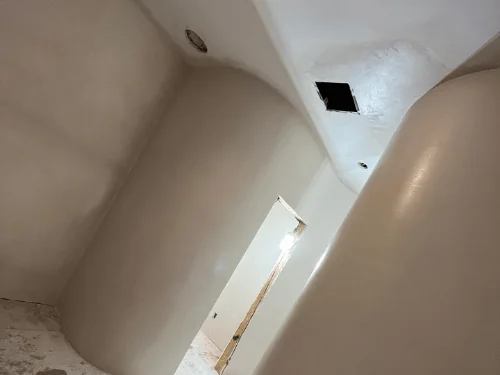 Rounded plaster wall forming a curved corner beside a doorway