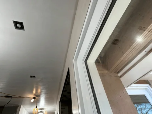 Long hallway with a smooth plastered ceiling and wood window jambs waiting for trim