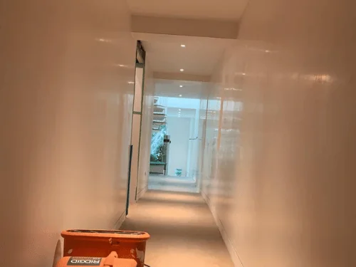 Long plastered hallway with a drying fan on the floor to cure the finish