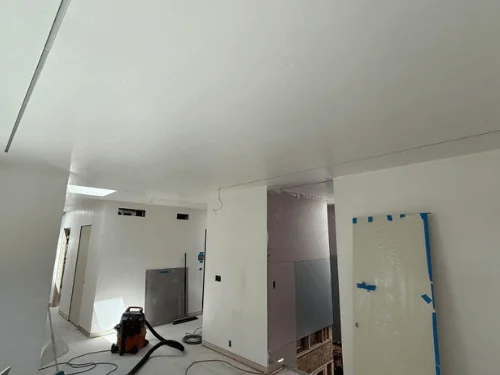 Open hallway in white plaster with a protected door leaning on the wall and a shop vacuum
