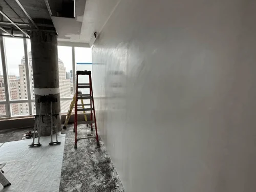 High-rise unit with a smooth plaster wall along the windows and steel ceiling framing still open above