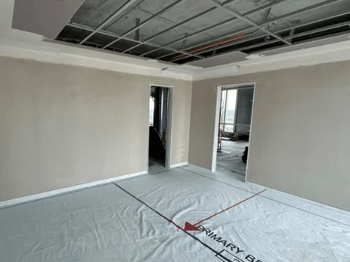 Bedroom in a high-rise unit with plastered walls and a perimeter soffit, steel ceiling grid still open