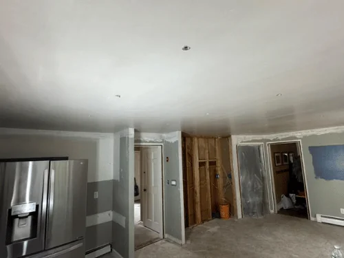 Kitchen renovation with a new smooth ceiling, an opened stud wall and patched board around the doors