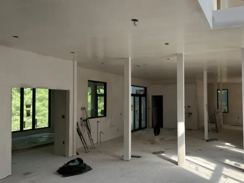 Open floor plan with a plastered ceiling, slim boxed columns and a skylight well