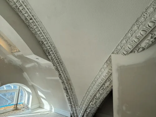 Vaulted ceiling with ornate plaster ribs meeting at the corner, new smooth plaster between them