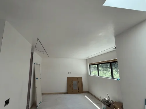 White plaster room with a sloped wall, a skylight and a strip of windows