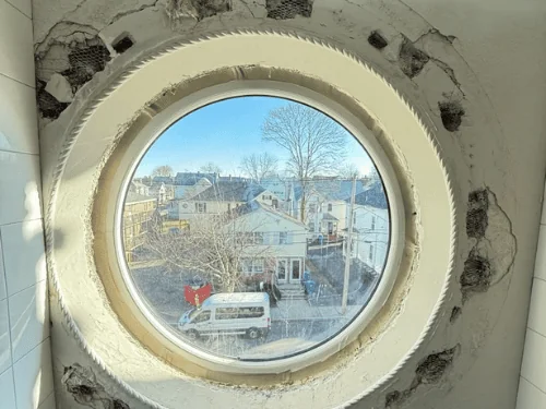 Close view of a round window surround with patches of missing plaster ready to be filled