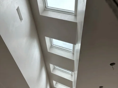 Plastered skylight wells in a sloped ceiling, each return finished smooth
