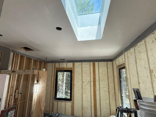 Plastered ceiling with a skylight well above walls still open to the studs