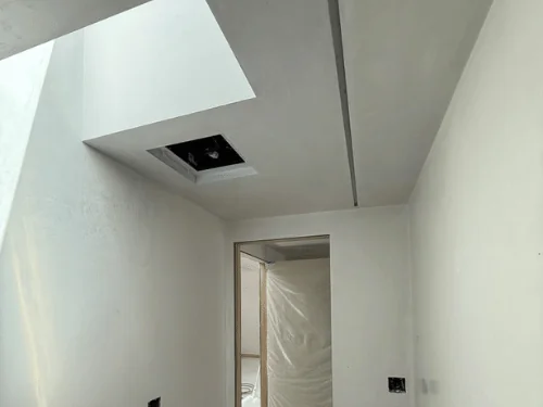 White plaster room with a deep skylight well and a doorway to the next space