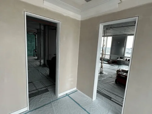 Two doorways under a plastered soffit with a tray edge, walls finished smooth