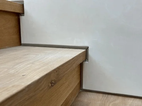 Close view of an oak stair tread set against a smooth plaster wall