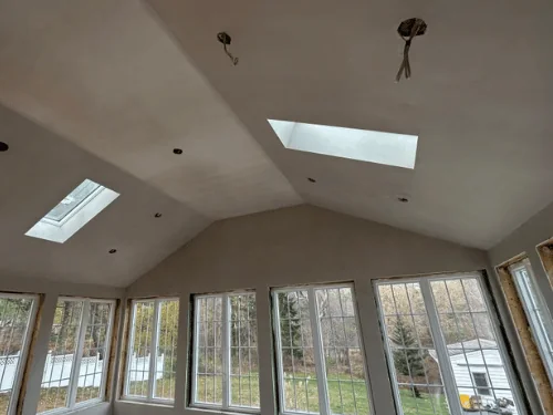 Sunroom with a vaulted plaster ceiling, two skylights and a full wall of windows