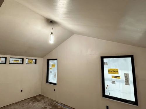 Vaulted room with smooth plaster walls and ceiling and new black-framed windows