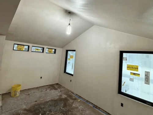 Plastered vaulted ceiling and walls with a row of small transom windows and a large picture window