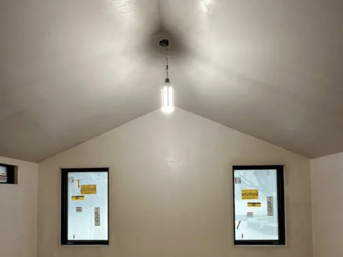 Cathedral ceiling and gable wall in smooth plaster between two tall windows