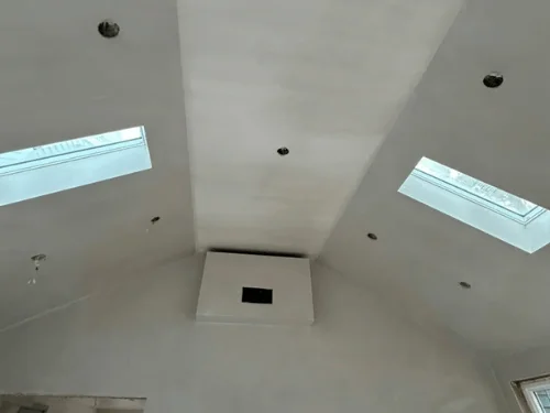 Cathedral ceiling with two skylights and a centered chase, finished in plaster